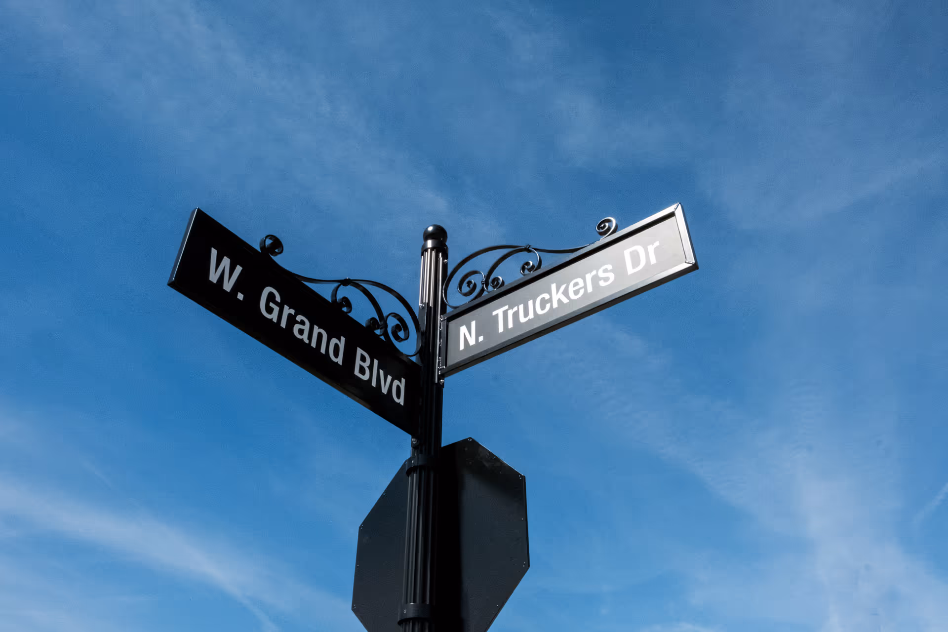 A street sign at the intersection of W. Grand Blvd and N. Truckers Dr against a clear blue sky.