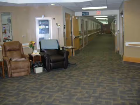 Interior corridor in a senior living center with seating and a flower arrangement.