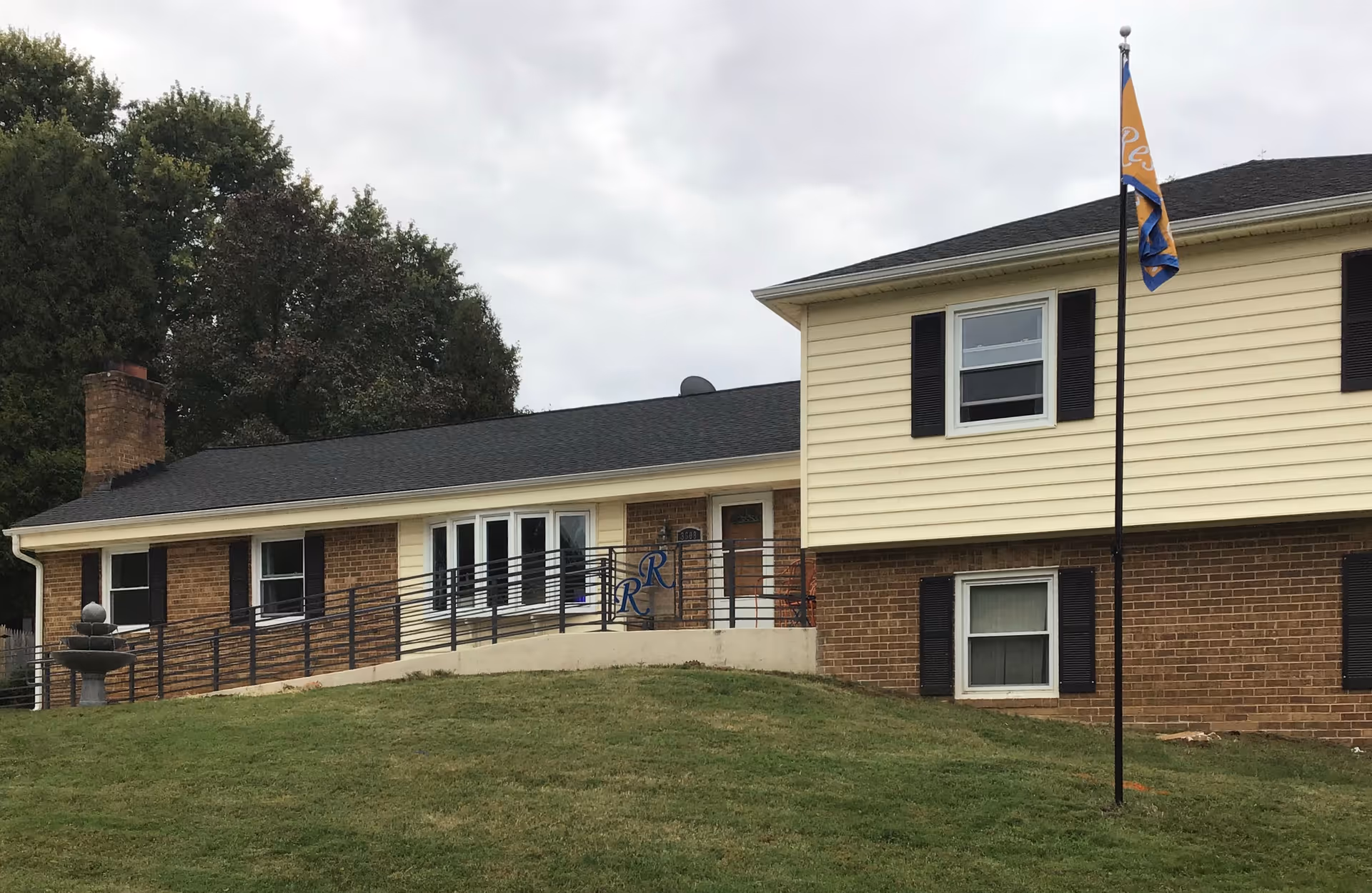 Exterior view of Russell Residence Assisted Living Home with brick base and light siding.