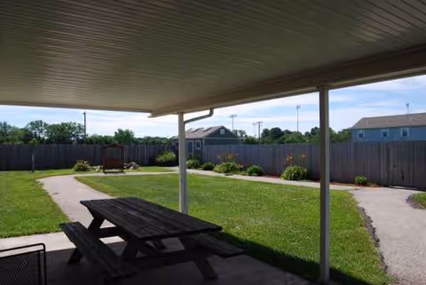 Covered patio with picnic table overlooks a grassy courtyard and walking paths.