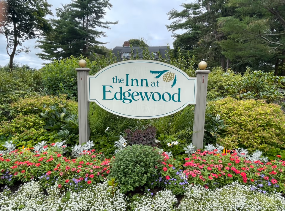 Entrance sign reading "the Inn at Edgewood" surrounded by flowers and greenery.