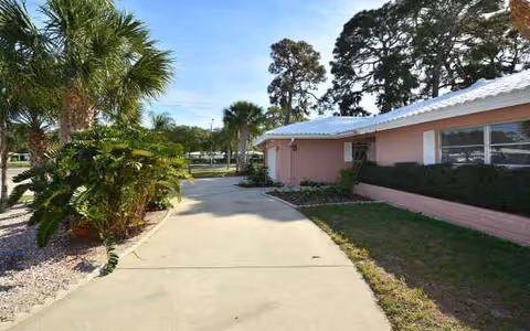 A pink, single-story facility with a sidewalk, palm trees, and landscaped exterior.