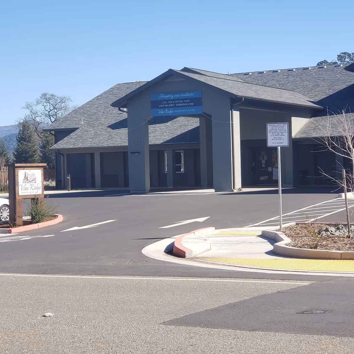 Exterior front entrance of Vine Ridge at Cloverdale showing the covered drive-up drop-off, signage, and parking area.