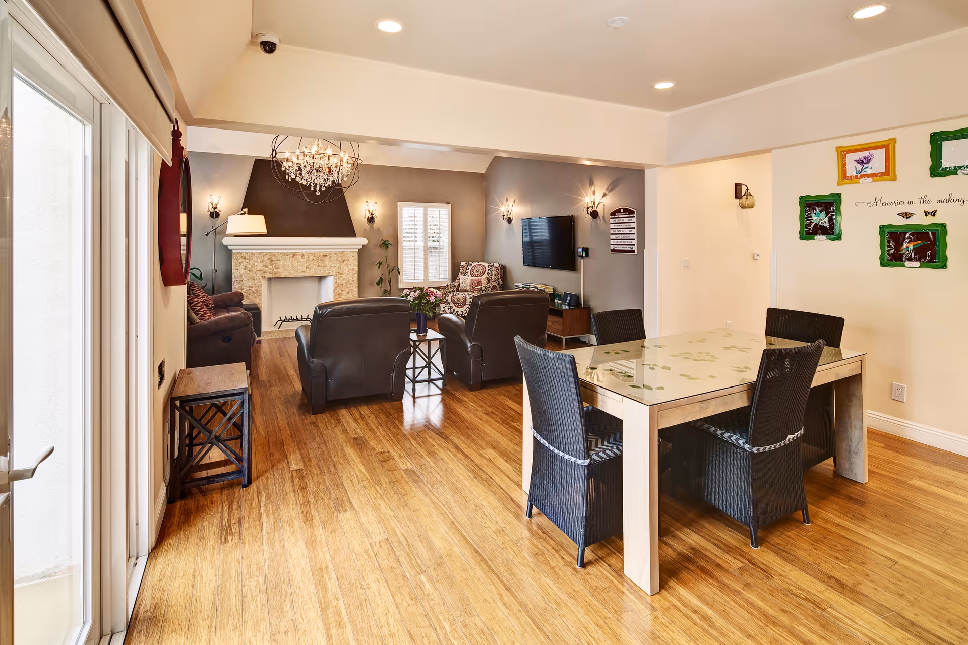 Spacious communal living area with a fireplace, chandelier, glass top dining table, and comfortable seating.
