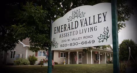 A large Emerald Valley Assisted Living sign stands in front of a building.