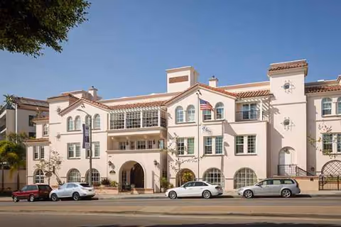 Exterior view of Atria Park of Pacific Palisades building with cars parked on street.