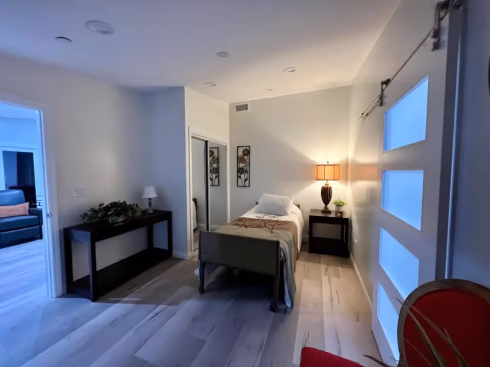 Small bedroom with a single bed, nightstand and lamp, mirrored closet doors, and a console table.
