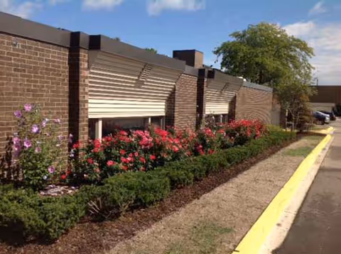 Exterior view of The Bellaire Senior Living building with brick walls, shutters, and landscaped walkway.