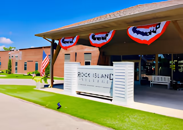 Entrance canopy and sign for Rock Island Village Assisted Living decorated with patriotic bunting and an American flag.