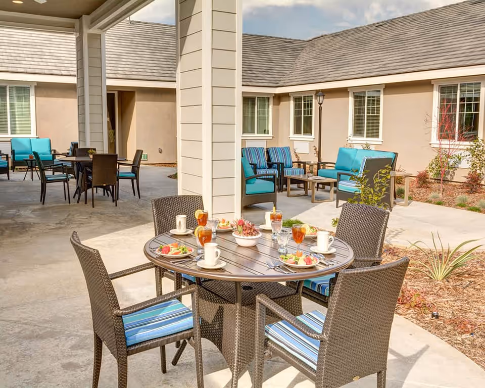 Outdoor courtyard with a round dining table set for meals and multiple cushioned seating areas and patio furniture.