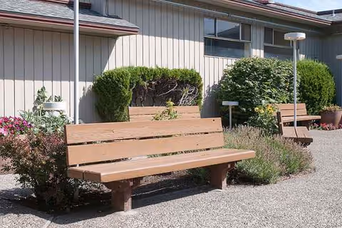 Outdoor seating area with wooden benches and shrubs beside the facility.