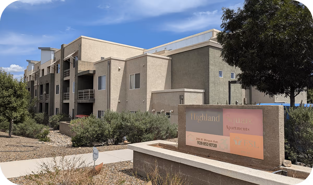 A beige multi-story building with a front sign reading Highland Square Apartments and desert landscaping.