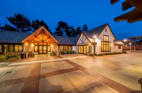Twilight exterior view of Villa Siena Senior Living Community with lit entry and courtyard.