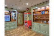 Interior common area with built-in cabinetry and shelving, a red popcorn/candy machine on a cart, and wood flooring.