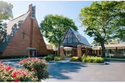 Exterior view of Four Seasons Retirement Center with brick walls, glass entry, and trees.