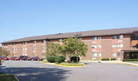 Exterior view of Hammond Elderly Apartments: brick senior living building with parking and trees.
