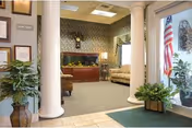 Lobby/lounge area with two white columns opening to sofas and a reception desk, potted plants, framed certificates, and an American flag by the entrance.
