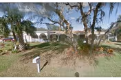 Exterior view of Harbor Oaks Golden Years showing front entrance, arches, lawn, and trees.