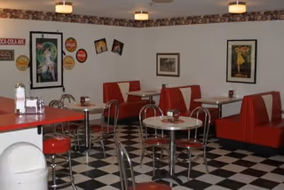 Retro-style dining room with red booths, chrome tables and a black-and-white checkered floor.