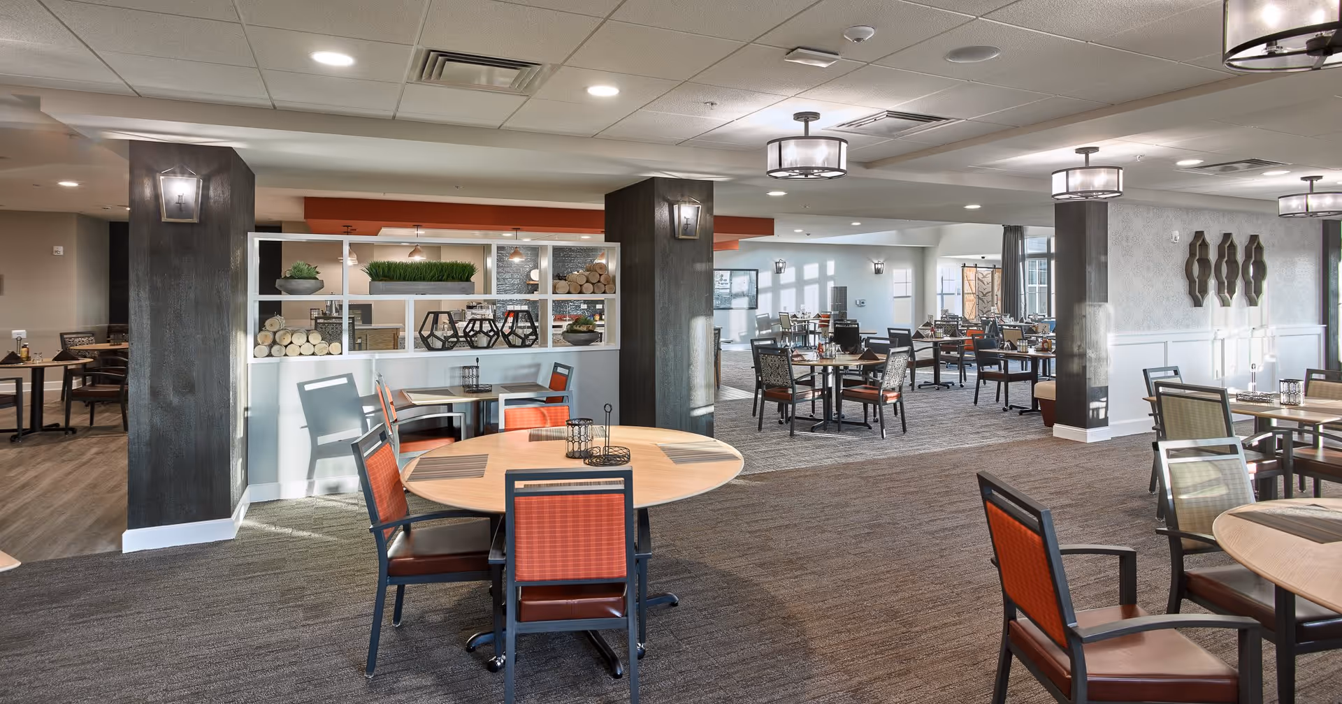 Spacious dining room with round tables and chairs, modern light fixtures, and decorative shelving.