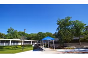 Exterior view of a senior living facility with a blue canopy and manicured grounds.