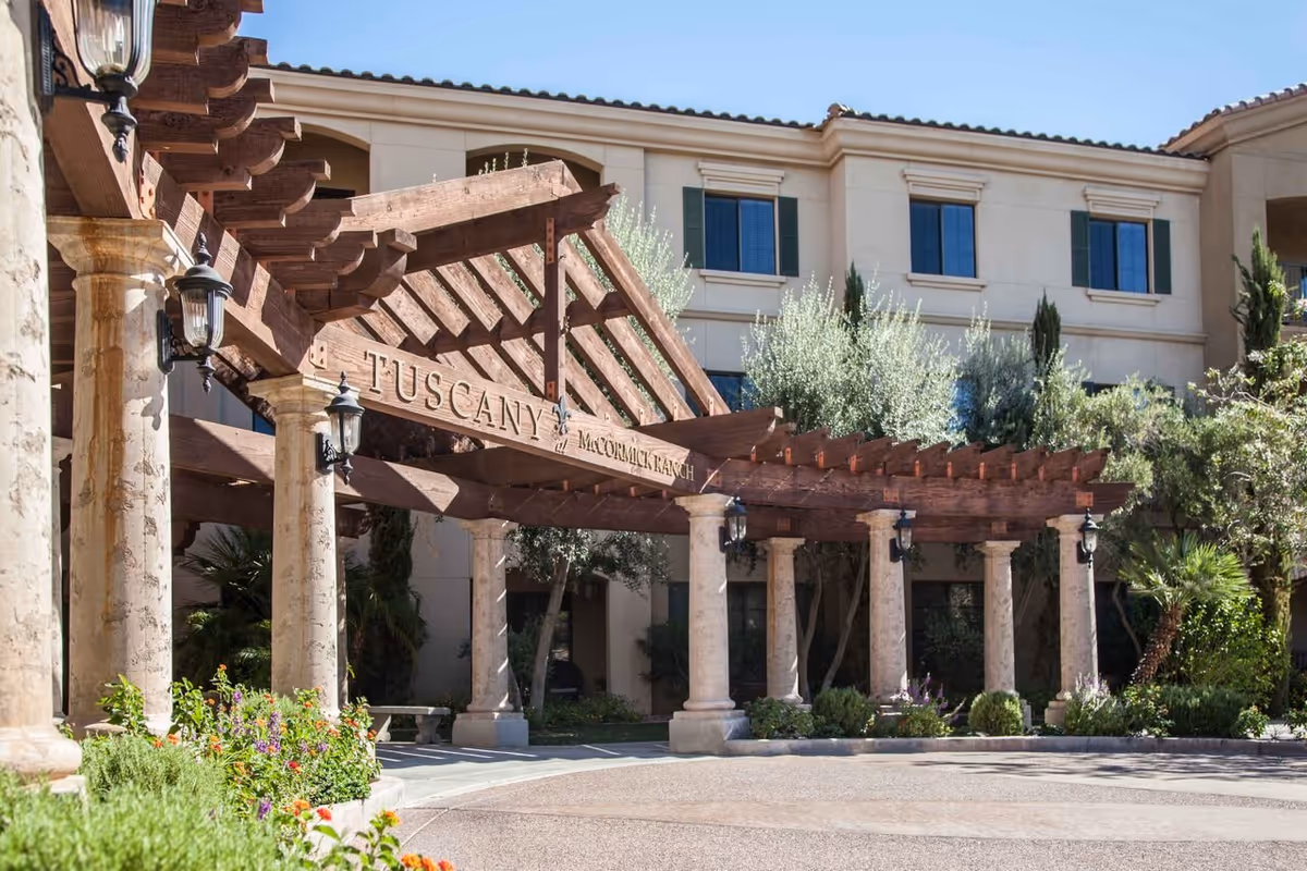 Front entrance of the Tuscany at McCormick Ranch building with a wooden pergola and stone columns.