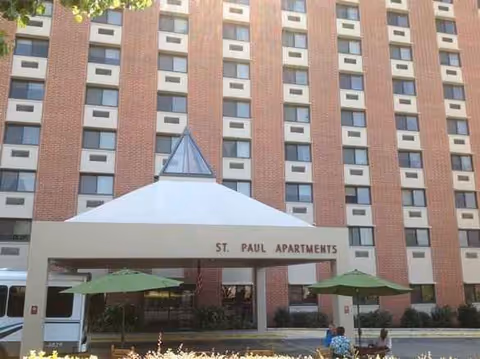 Exterior view of St. Paul Apartments building with entrance canopy and outdoor seating.