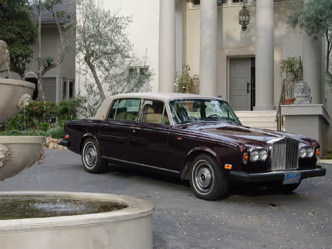 A classic dark sedan parked before a grand columned entrance at Peppers Estate.