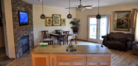 Open living area with kitchen island, dining table, couch, and wall-mounted TV.