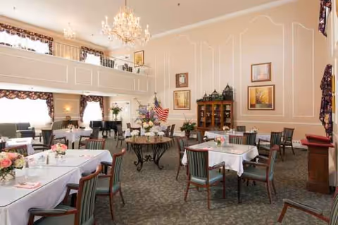 Elegant dining room with round tables, white linens, flowers, and chandeliers.