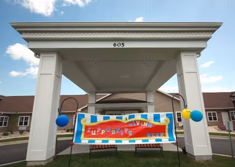 Front entrance canopy of Fox Meadows Supportive Living with a colorful banner and balloons.