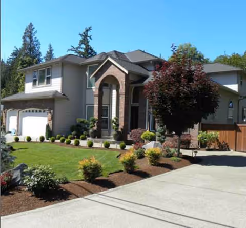 A residential-style senior living facility with a manicured front yard and driveway.