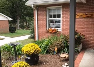 Exterior view of The Perryman House with brick facade, window box, and blooming flowers.