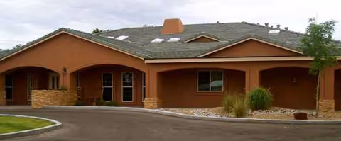Exterior view of a single-story brown senior living facility with arches and a curved driveway.