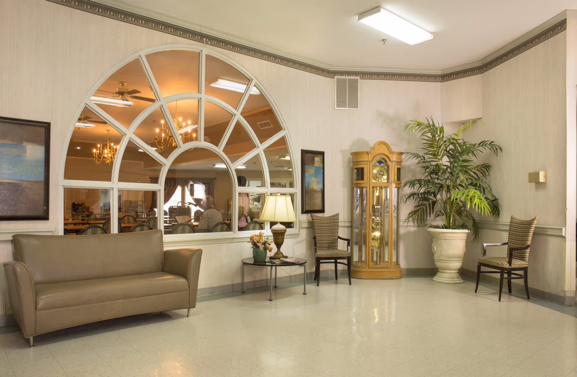 A spacious interior of Heather Manor Rehabilitation featuring a seating area with a sofa, chairs, a plant, and a decorative clock.