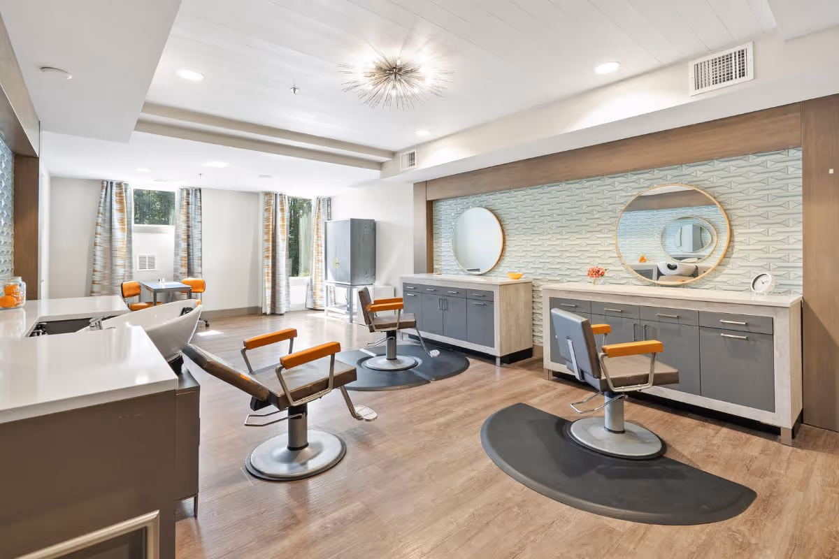 Bright salon-style interior with styling chairs, round mirrors, a wash basin, and cabinetry.