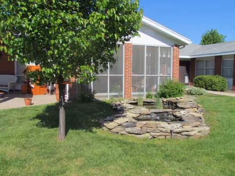 Front view of a single-story senior living building with a stone water feature.