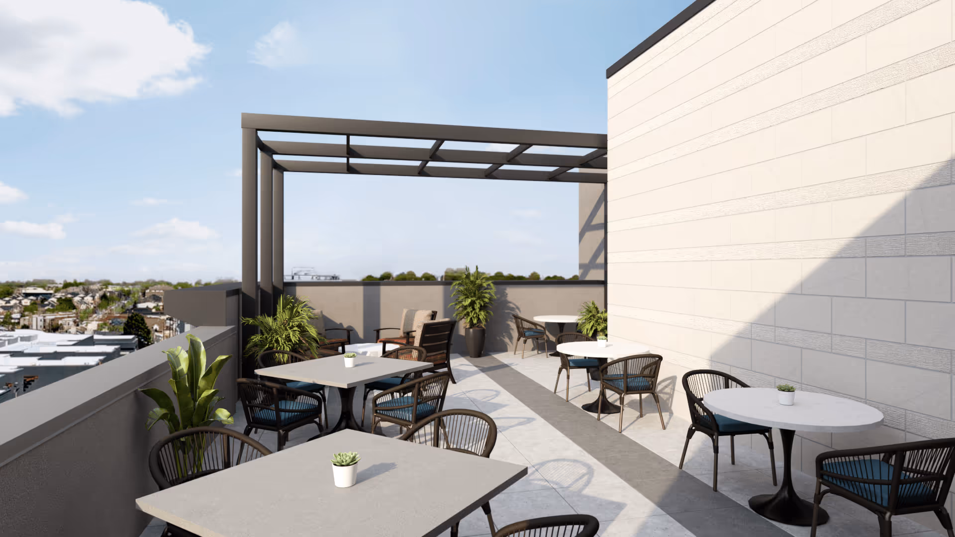 Outdoor patio area with several tables and chairs arranged for seating, decorated with small potted plants on each table and larger potted plants along the perimeter. The space has a partial pergola overhead and overlooks a distant neighborhood under a partly cloudy sky.