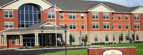 Paramount Senior Living at Manassas exterior with brick facade, arched windows, and flag.