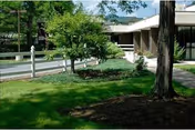 Exterior view of a senior living facility with lawn, trees, and a front entrance.