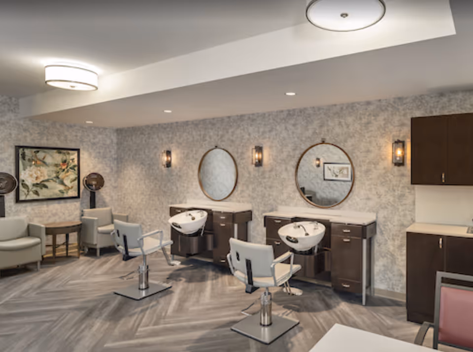 Interior salon area with styling chairs, shampoo basins, round mirrors, and seating.