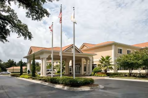 Front entrance of Life Care Center Pensacola with porte-cochère and flags.