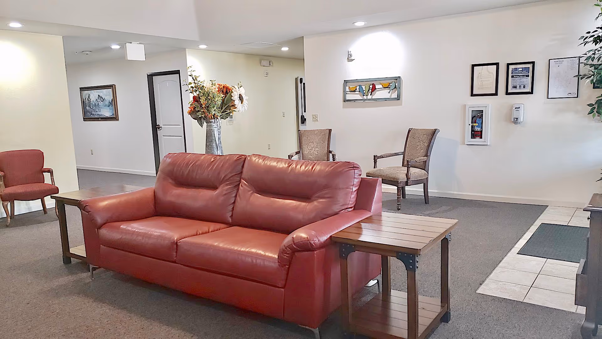 Lobby/common area with a red leather sofa, side tables, additional chairs, and wall décor.