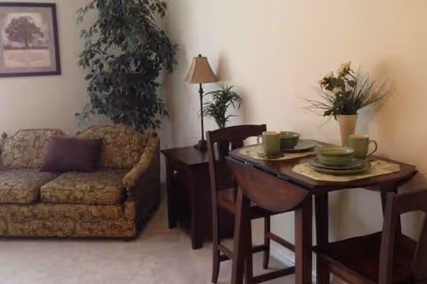 Cozy living area with sofa, plants, and a dining table set.