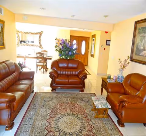Lobby inside Cheerful Heart Home Care III with brown leather seating, rug, and plants.