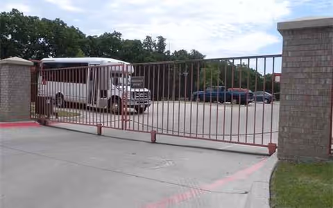 Gate entrance to Amelia Parc with a bus parked near the curb.