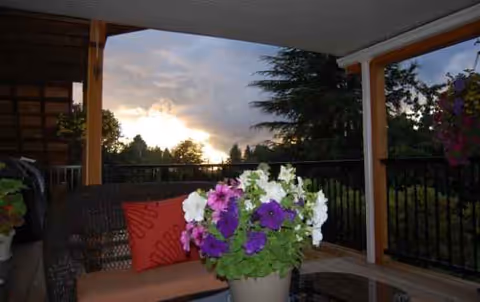 Outdoor patio area at sunset with potted flowers and wicker seating.