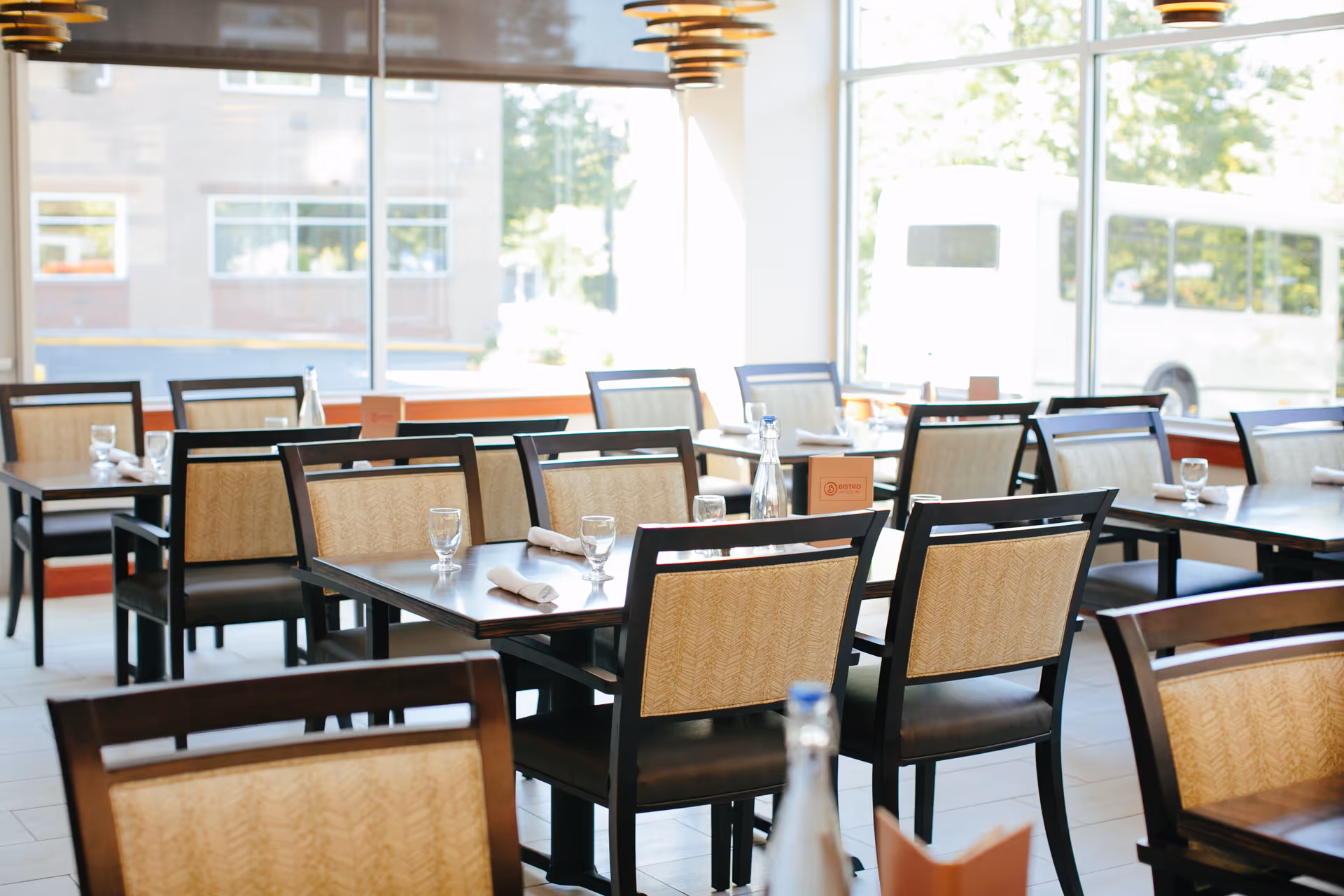 Bright dining room with multiple tables and chairs set near large windows