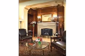 Cozy living room lounge with a fireplace, ornate wood paneling, and glass coffee table.