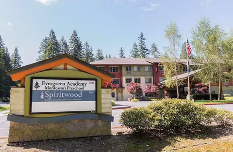 Front exterior of a building with a large sign and landscaped entrance.
